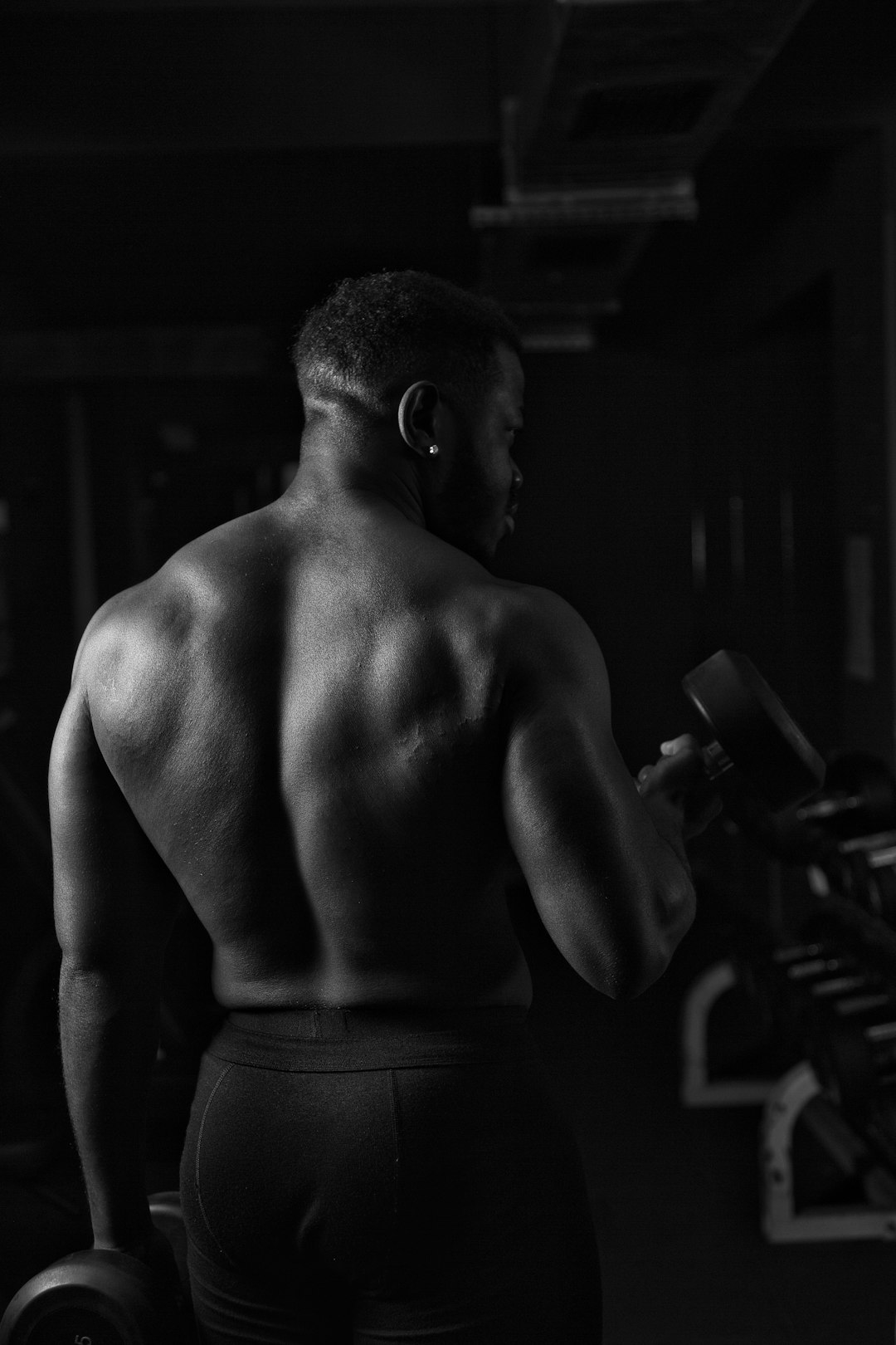 a man with no shirt is holding a barbell